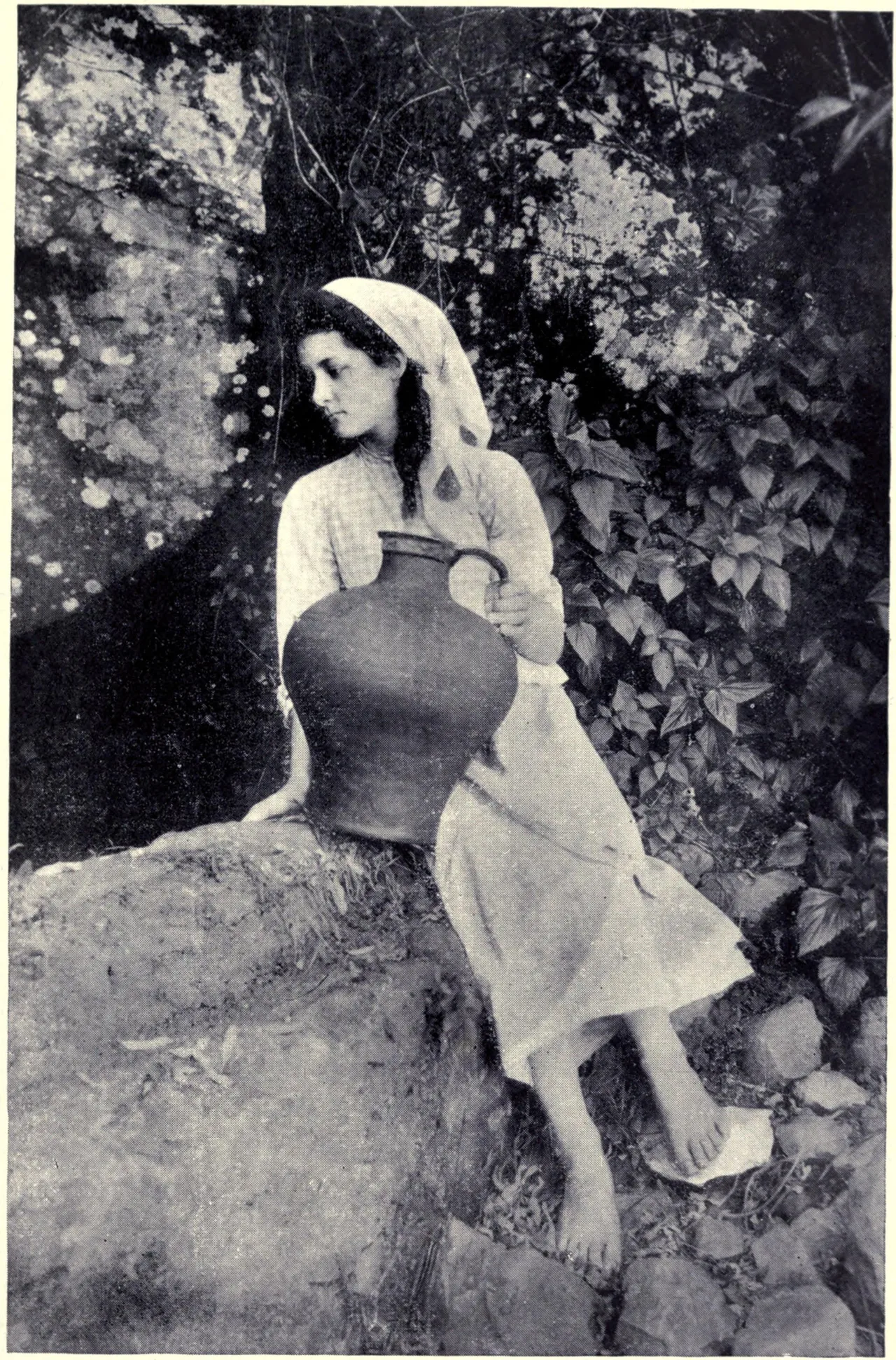 A girl standing beside a levada in 1909 holding a water pot on her head